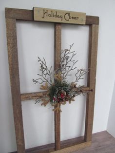 a wooden frame with a holiday cheer sign on it and some branches in the center