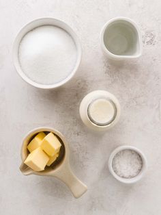 ingredients to make cheesecake sitting on a white counter top, including butter and sugar