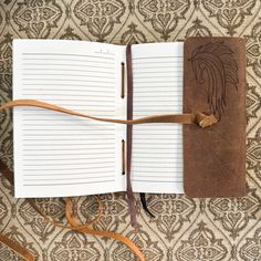 an open notebook with a brown leather cover and string attached to it on a patterned surface