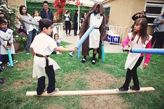 two children are playing with an inflatable baseball bat while others watch from the back yard