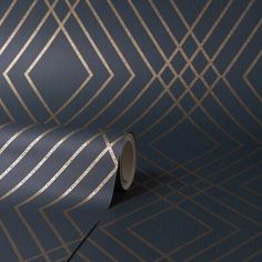 a blue and gold wallpaper with geometric lines on the side, along with a roll of tape