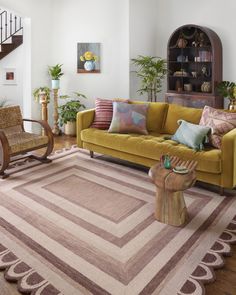 a living room with yellow couches and rugs on the floor, wooden furniture