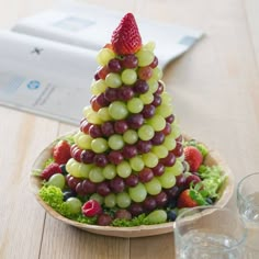 a small christmas tree made out of grapes and strawberries