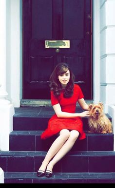 a woman in a red dress sitting on steps with her dog