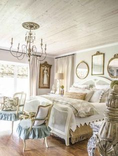 a bedroom with a bed, chairs and chandelier