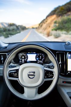 the interior of a volvo car on a road with mountains in the backgroud