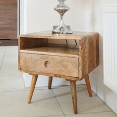 a small wooden table with a lamp on it's top and drawers underneath the shelf