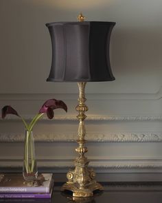 a lamp that is on top of a table next to a vase with flowers in it