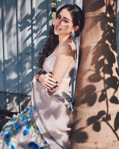 a woman leaning against a tree wearing a dress