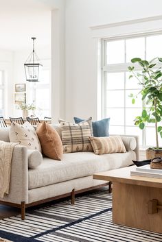 a living room filled with lots of pillows on top of a couch next to a window