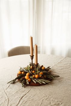 two candles sitting on top of a table with oranges