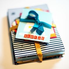 a gift card with a blue bow on it sitting on top of a pile of books