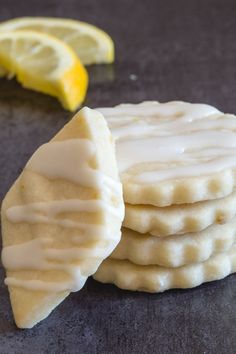 a stack of lemon shortbreads sitting on top of a table next to a slice of lemon