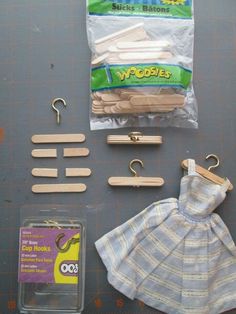 some clothes hangers and wooden pegs on a table next to a bag of paper clips