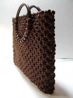 a crocheted brown purse sitting on top of a white table