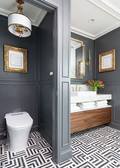 a white toilet sitting next to a sink in a bathroom under a mirror on top of a wall