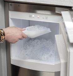 a person reaching into an open refrigerator filled with ice and water to grab something out