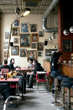 people sitting at tables in a restaurant with pictures on the wall