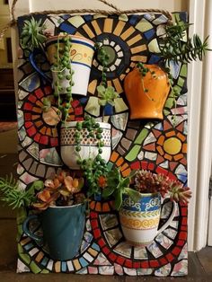 there are many potted plants on this mosaic wall hanging from the side of a building