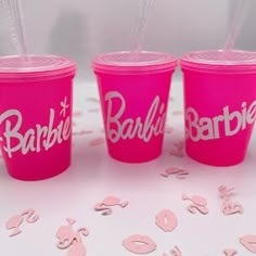 three pink plastic cups with straws in each one that say barbie, barbie and barbie