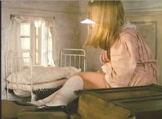 a woman sitting on top of a bed next to a white crib in a room