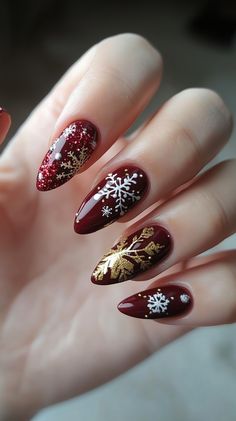 A hand with five fingers showcasing elegant Christmas nail designs featuring deep red and gold accents, snowflake patterns, and glitter tips. The background is softly blurred, creating a festive, cheerful atmosphere. Velvet Nails, Festive Nail Art, Matte Red, Festival Nails, Christmas Nail Designs, Holiday Outfit, Christmas Nail, Accent Nails, Christmas Nail Art