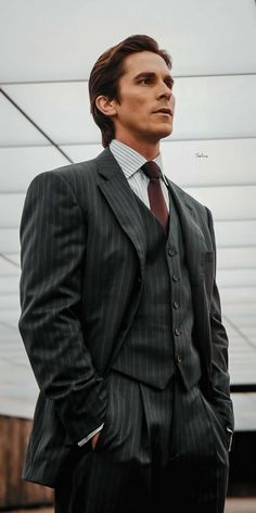 a man wearing a suit and tie standing in front of a building