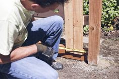 a man kneeling down next to a wooden structure