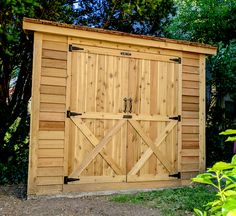 a large wooden shed sitting next to a lush green forest