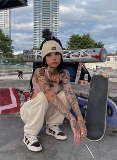 a woman sitting on the ground holding a skateboard