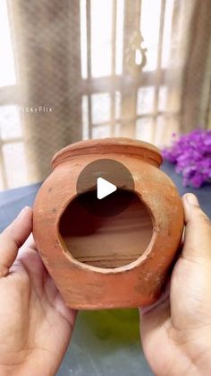 a person holding a clay pot with the opening