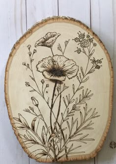 a piece of wood with flowers painted on it and some leaves in the middle, hanging on a wall