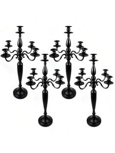 six black candlesticks are lined up in the shape of a candelabra