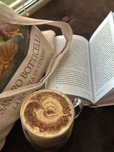 a cup of coffee next to an open book