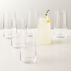 several glasses are lined up next to each other on a table with a drink in the middle