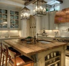 a kitchen with an island made out of wood and lights hanging from it's ceiling