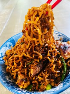 a blue plate topped with noodles and meat