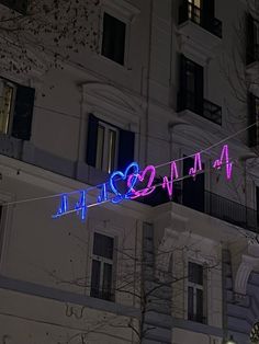 a neon sign that is hanging from a wire in front of a building at night