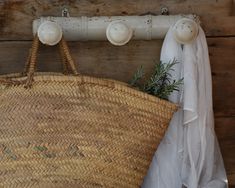 a woven basket hanging on a wooden wall with three white knobs attached to it