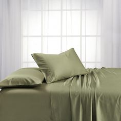 a bed covered in green sheets and pillows