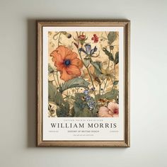 a framed poster hanging on the wall above a vase with an orange and blue flower