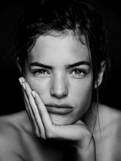 a beautiful young woman with blue eyes posing for a photo in front of a black background