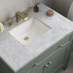 a bathroom sink with marble counter top and gold faucet handles on the side