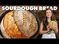 a woman holding a loaf of bread in front of a round pan with the words sourdough bread on it