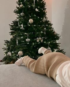 a small child laying on top of a bed next to a christmas tree with lights