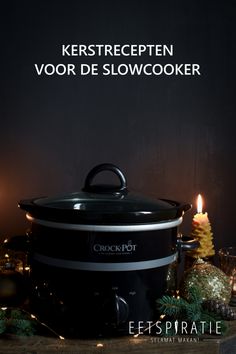 a black crock pot sitting on top of a table next to a lit candle