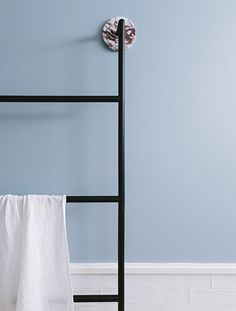 a towel rack in the corner of a room with blue walls and white tile flooring