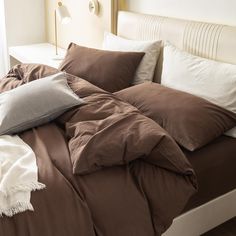 an unmade bed with brown and white pillows