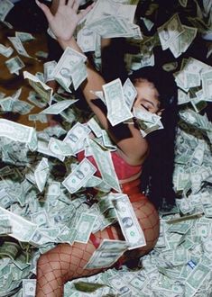 a woman in fishnet stockings is surrounded by dollar bills and her hands are up