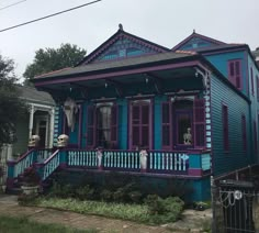 a blue house with purple trim and red shutters on the front porch is shown